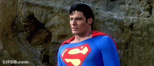 A Man In A Superman Costume Stands In Front Of A Rock GIF