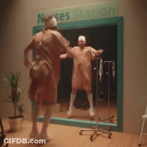 A Man In A Surgical Gown Is Dancing In Front Of A Sign That Says Nurse Station GIF