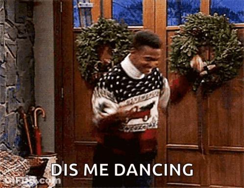 A Man In A Sweater Is Dancing In Front Of A Door With A Wreath Hanging On It . GIF