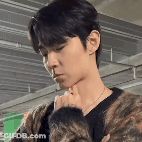 A Man In A Sweater Is Holding His Hand To His Chin . GIF