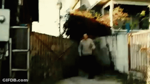 A Man In A Sweater Is Running Down A Sidewalk GIF