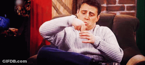 A Man In A Sweater Is Sitting In A Chair With His Legs Crossed . GIF