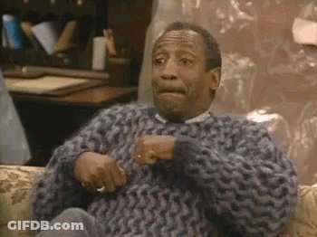 A Man In A Sweater Is Sitting On A Couch And Making A Face . GIF