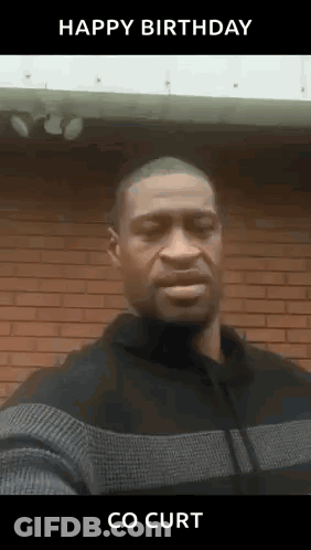 A Man In A Sweater Is Standing In Front Of A Brick Wall And Says Happy Birthday Co Curt . GIF