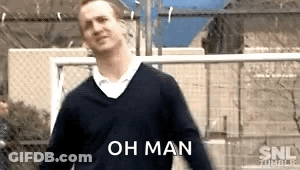 A Man In A Sweater Is Standing In Front Of A Fence With The Words Oh Man Written On It . GIF