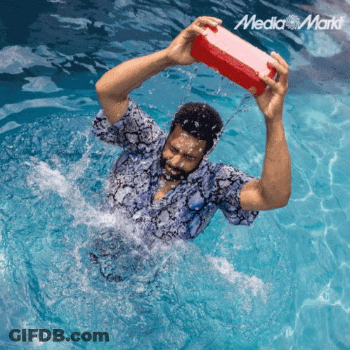 A Man In A Swimming Pool Is Holding A Red Box Over His Head With The Media Markt Logo In The Corner GIF