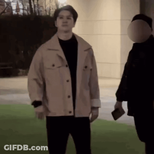 A Man In A Tan Jacket Is Standing Next To A Man In A Black Shirt GIF
