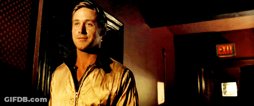 A Man In A Tan Jacket Stands In Front Of An Exit Sign GIF