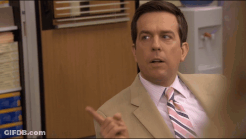 A Man In A Tan Suit And Pink And Blue Striped Tie Is Pointing GIF