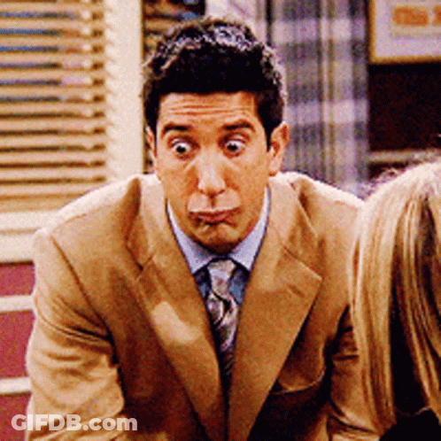 A Man In A Tan Suit And Tie Making A Funny Face GIF