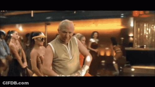 A Man In A Tan Tank Top Is Dancing In Front Of A Crowd GIF