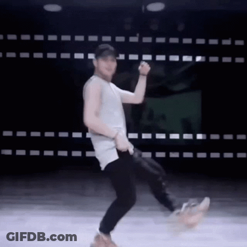 A Man In A Tank Top And Black Pants Is Dancing On A Stage . GIF