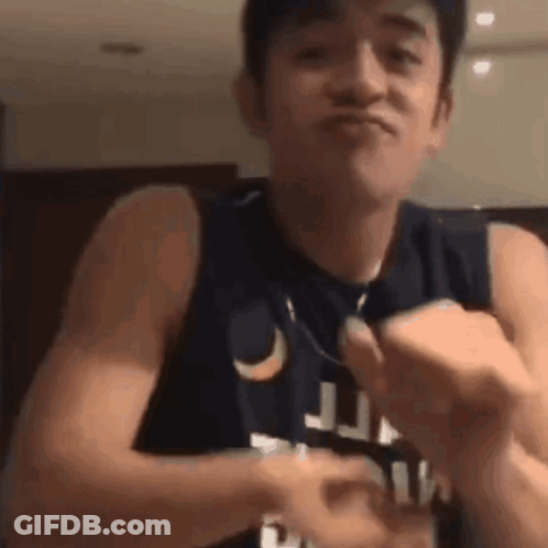 A Man In A Tank Top Is Making A Funny Face While Holding Something In His Hands . GIF