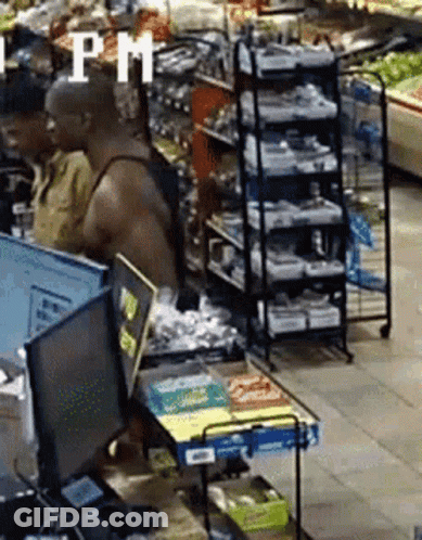 A Man In A Tank Top Is Standing In Front Of A Computer In A Grocery Store With A Sign That Says Pm GIF