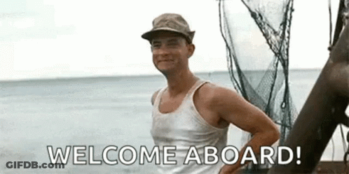 A Man In A Tank Top Is Standing On A Boat In The Ocean And Saying Welcome Aboard . GIF