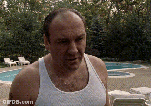 A Man In A Tank Top Stands In Front Of A Swimming Pool GIF