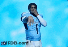 A Man In A Tennessee Titans Jersey Is Dancing In Front Of A Blue Background . GIF