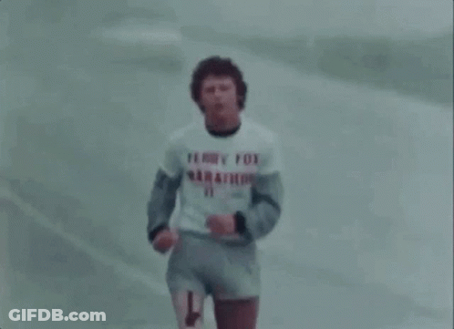 A Man In A Terry Fox Marathon Shirt Is Running On A Road . GIF