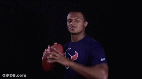 A Man In A Texans Shirt Is Holding A Football In His Hand . GIF