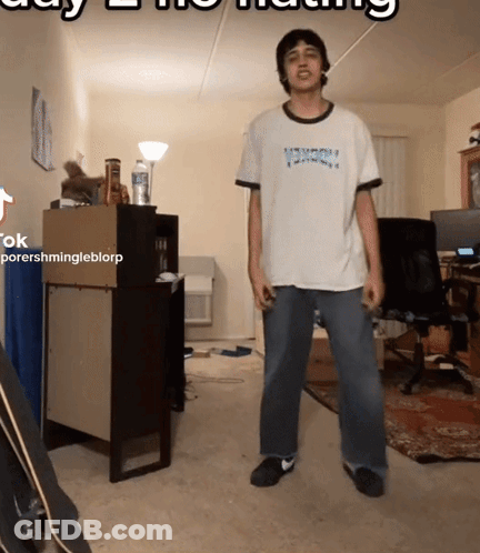 A Man In A Thrasher Shirt Is Standing In A Room GIF