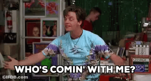 A Man In A Tie Dye Shirt Is Standing In Front Of A Record Store . GIF