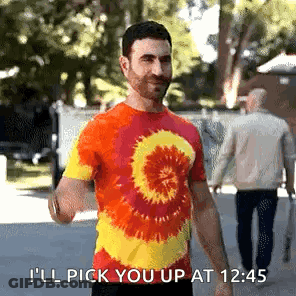 A Man In A Tie Dye Shirt Says I 'Ll Pick You Up At 12:45 . GIF