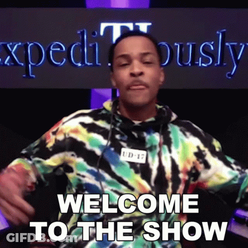 A Man In A Tie Dye Shirt Says Welcome To The Show In Front Of A Sign That Says Expeditously GIF