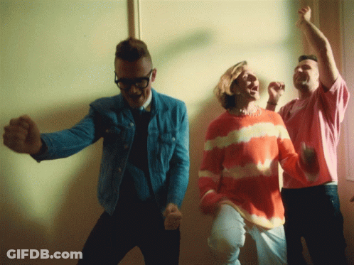 A Man In A Tie Dye Sweater Is Dancing With Two Other People GIF