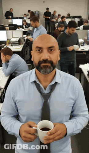 A Man In A Tie Holds A Cup Of Coffee In An Office GIF