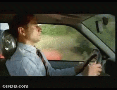 A Man In A Tie Is Driving A Car GIF