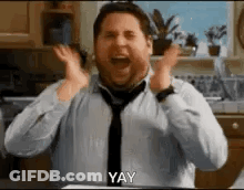 A Man In A Tie Is Making A Funny Face In A Kitchen . GIF