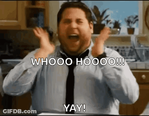 A Man In A Tie Is Making A Funny Face In A Kitchen With His Hands In The Air . GIF