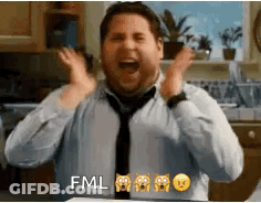 A Man In A Tie Is Making A Funny Face With His Hands In The Air In A Kitchen . GIF