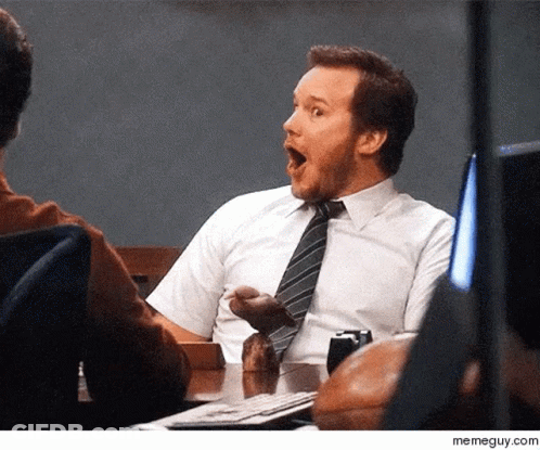 A Man In A Tie Is Sitting At A Desk With His Mouth Open GIF