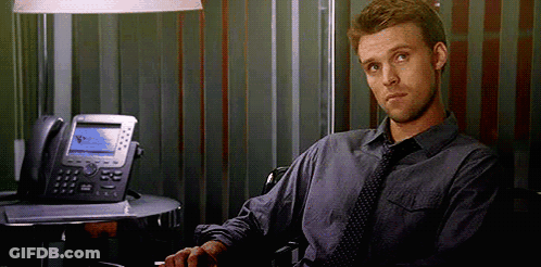 A Man In A Tie Is Sitting In Front Of A Desk With A Telephone . GIF