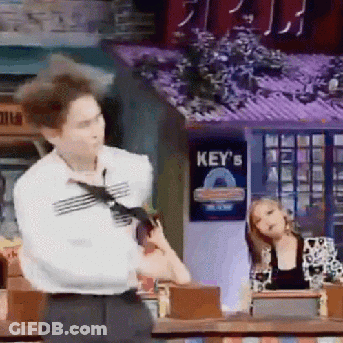 A Man In A Tie Is Standing In Front Of A Sign That Says Key 'S On It . GIF