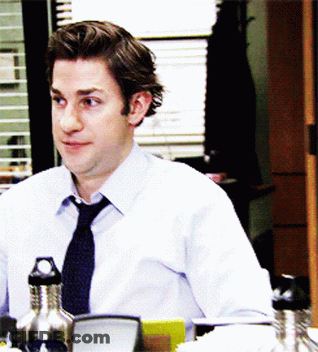 A Man In A Tie Sits At A Desk With A Water Bottle In Front Of Him GIF