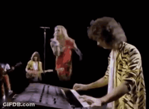 A Man In A Tiger Print Shirt Is Playing A Keyboard In Front Of A Group Of Musicians . GIF