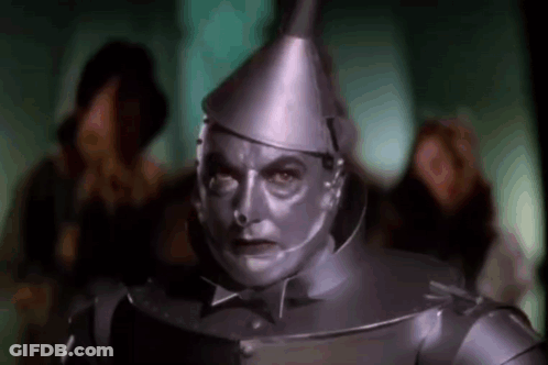 A Man In A Tin Man Costume From The Wizard Of Oz Is Standing In Front Of A Crowd Of People . GIF