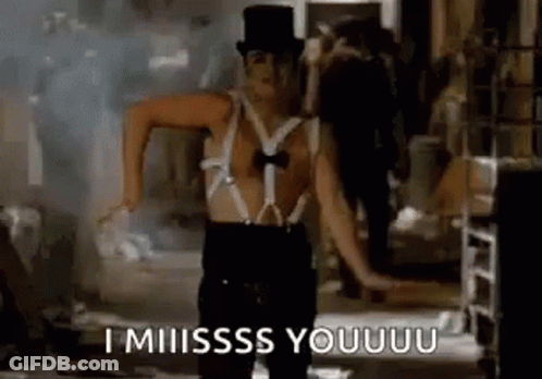 A Man In A Top Hat And Suspenders Is Dancing In A Dark Room . GIF