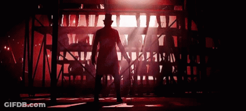 A Man In A Top Hat Is Dancing In A Dark Room With Red Lights . GIF