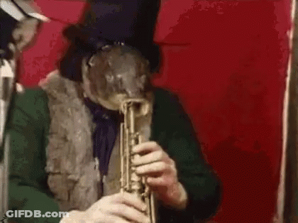 A Man In A Top Hat Is Playing A Trumpet In Front Of A Red Background . GIF