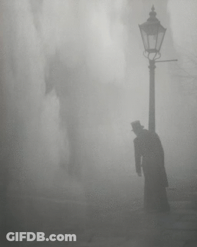 A Man In A Top Hat Is Standing Next To A Street Light GIF