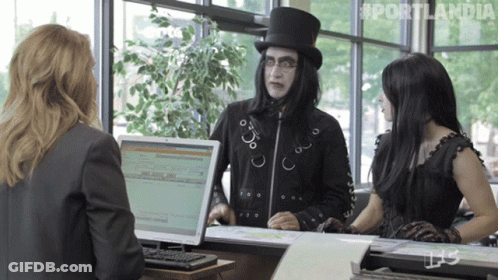 A Man In A Top Hat Is Talking To Two Women In Front Of A Computer Screen That Says Portlandia On It GIF