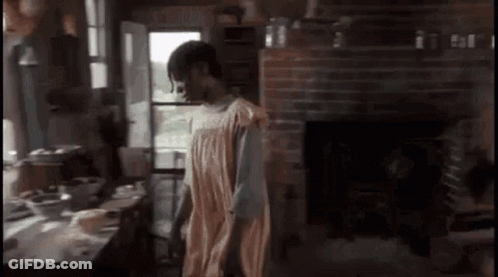 A Man In A Towel Is Standing In A Room With A Fireplace . GIF