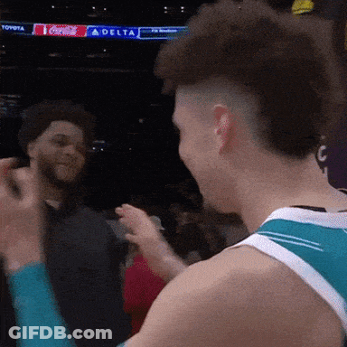 A Man In A Toyota Jersey Talks To Another Man In Front Of A Delta Sign GIF