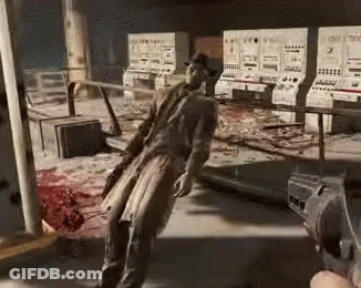 A Man In A Trench Coat Is Standing In A Room With A Gun In His Hand . GIF