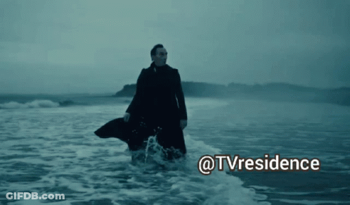 A Man In A Trench Coat Is Walking In The Ocean With The Words @Tvresidence Above Him GIF