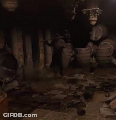 A Man In A Trench Coat Is Walking Through A Dark Room GIF