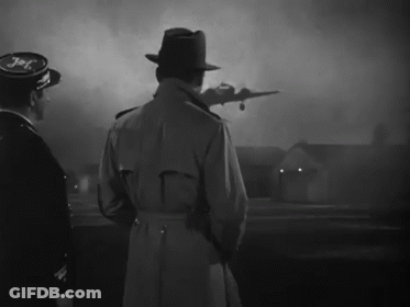 A Man In A Trench Coat Stands In Front Of A Plane That Says Jet GIF